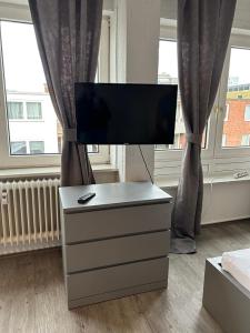 uma televisão numa cómoda num quarto com janelas em Gästezimmer 11 Citynah, Küche & Bad extern em Hamburgo