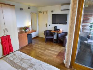 a room with a living room with a table and a television at Hotel De Kommel in Voeren