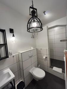 uma casa de banho com um WC, um lavatório e um lustre em Ferienwohnung Bauernliebe 43 Citynah, urban Cowboystyle em Hamburgo