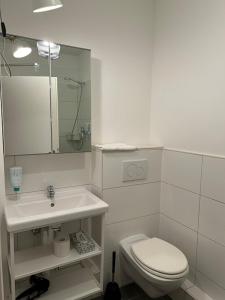 La salle de bains blanche est pourvue de toilettes et d'un lavabo. dans l'établissement Ferienwohnung Watzmann-Stüberl 51 gehobene Ausstattung, à Hambourg