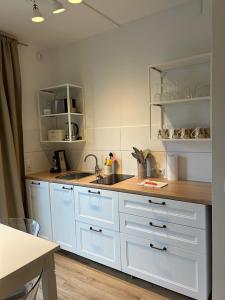 a kitchen with white cabinets and a wooden counter top at Studio- Apartment Hirschwiese 52 "cozy" für zwei in Hamburg