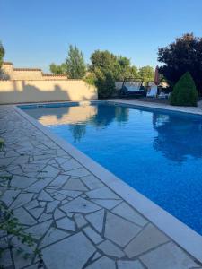a swimming pool with a stone walkway next to a house at hOTEL kARINA in Jarnac