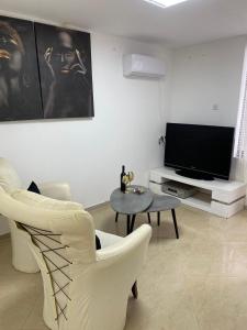 - un salon avec une télévision, une table et des chaises dans l'établissement בקתת אברהם, à Safed