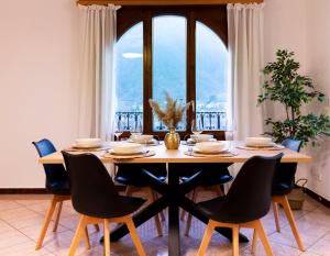 een eettafel met stoelen en een groot raam bij 4.5 locali magnifica vista lago e parking pubblico in Mendrisio