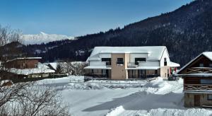 uma casa coberta de neve com montanhas ao fundo em Sky-House Jasná Apartments em Pavčina Lehota