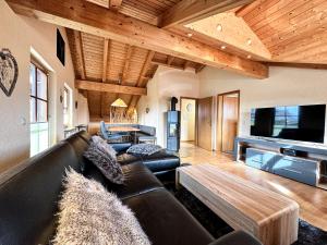 a living room with a leather couch and a tv at FeWo "Sonnenschein" Oberreute in Oberreute