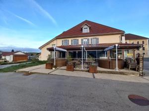 une maison avec un restaurant doté de tables et de parasols dans l'établissement Hôtel *** Les Tremplins, à La Chaux Neuve