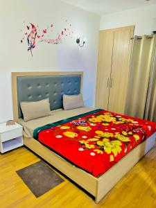 een slaapkamer met een bed met een rode deken met bloemen bij Couple Stay In Near By Sector 142 Metro And Near By Expo Mart By GALAXY INN in Noida
