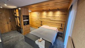 Habitación con 1 cama en una habitación con paredes de madera. en Rezidence Alpina - Apartmán 15 en Špindlerův Mlýn