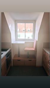 a small kitchen with a window and a pink chair at Montel PARK - Stockholm in Linz