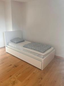 a white bed with two pillows on a wooden floor at Montel PARK - Stockholm in Linz