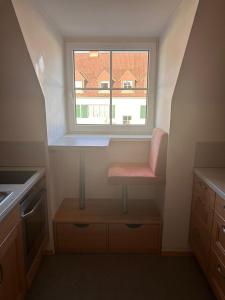 a small kitchen with a pink chair under a window at Montel PARK - Stockholm in Linz