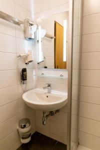 ein Bad mit einem Waschbecken und einem Spiegel in der Unterkunft Metzgerwirt Vieh Heli in Bad Goisern