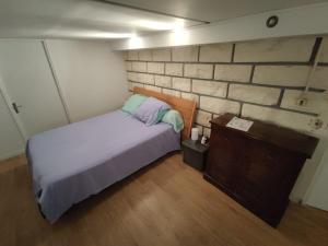 ein kleines Schlafzimmer mit einem Bett und einer Holzkommode in der Unterkunft Studio privé dans maison in Le Plessis-Trévise
