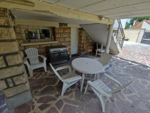 eine Terrasse mit einem Tisch, Stühlen und einem Herd in der Unterkunft Studio privé dans maison in Le Plessis-Trévise