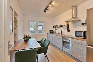 een keuken met een houten tafel en groene stoelen bij Villa trifft Zeche by Cordis Sky für bis zu 7 Personen 5 Minuten zur Messe Essen und zum Hauptbahnhof Essen in Essen