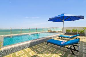 a swimming pool with two chairs and an umbrella at Palazzo Boutique Hotel in Danang