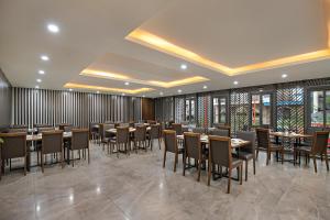 a dining room with tables and chairs and windows at Palazzo Boutique Hotel in Danang