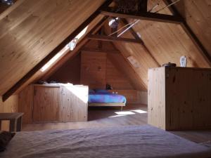 1 dormitorio en un ático con cama y techo de madera en Bienvenue chez vous, en Le Merzer