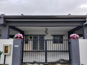 a house with a gate with flowers on it at Rabb Homestay Samarahan in Kampong Setigang