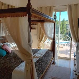 a bedroom with a canopy bed and a balcony at Sunset Boutique Guest House in Paphos City