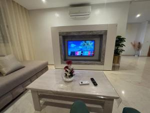 uma sala de estar com um sofá e uma televisão em Appart de luxe 27 ILOT9 em Oujda