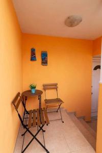 a table and chairs in a room with an orange wall at Vaso apartment Limenaria Thasos in Limenaria