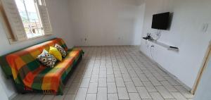 a living room with a couch and a television at Apartamento Guriri Verão in São Mateus