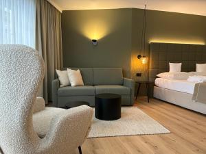 ein Hotelzimmer mit einem Bett, einem Sofa und einem Stuhl in der Unterkunft Das Schlössl in Haiming