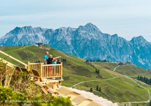 Appartements Kuckuck Leogang في ليوغانغ: مجموعة من الناس تقف على سطح ملاحظة مع الجبال