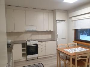a kitchen with white cabinets and a table and a dining room at Saunallinen rivitalohuoneisto B5 59m2 in Säviä