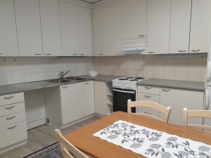 a kitchen with white cabinets and a table and chairs at Saunallinen rivitalohuoneisto B5 59m2 in Säviä