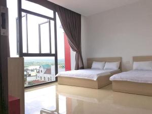 2 Betten in einem Zimmer mit einem großen Fenster in der Unterkunft NGOC PHUNG HOTEL in Ban Blech