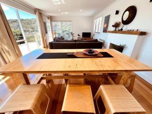 a wooden table and benches in a living room at The Coles Bay Shack - Freycinet in Coles Bay