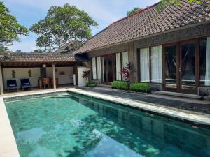 a swimming pool in front of a house at Nefatari Exclusive Villas in Ubud