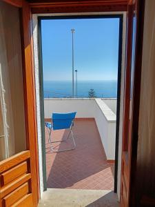 eine Glasschiebetür mit einem blauen Stuhl auf dem Balkon in der Unterkunft Appartamento vista mare a 10 minuti da Castro Marina in Andrano