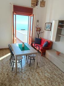 ein Wohnzimmer mit einem Tisch, Stühlen und einem Sofa in der Unterkunft Appartamento vista mare a 10 minuti da Castro Marina in Andrano