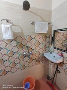 a bathroom with a sink and a mosaic wall at Suraj Guest House in Varanasi