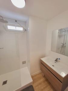 Baño blanco con lavabo y espejo en Logement grand confort, en Laval