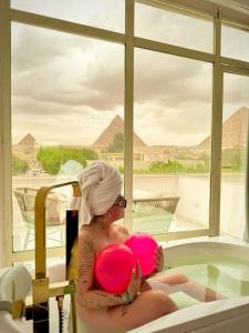 une femme assise dans une baignoire tenant un ballon rose dans l'établissement Tree Lounge Pyramids View INN , Sphinx Giza, au Caire