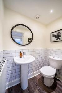 W łazience znajduje się toaleta, umywalka i lustro. w obiekcie Tranquil Riverfront Oasis at High Bridge Court w mieście Knaresborough