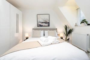 biała sypialnia z łóżkiem z 2 ręcznikami w obiekcie Tranquil Riverfront Oasis at High Bridge Court w mieście Knaresborough