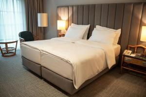1 cama blanca grande en una habitación de hotel en Eventhotel Pyramide, en Vösendorf