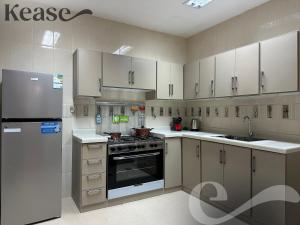 a kitchen with white cabinets and a stove and refrigerator at Kease Al-Mutamarat A-12 Timeless History AZ11 in Riyadh