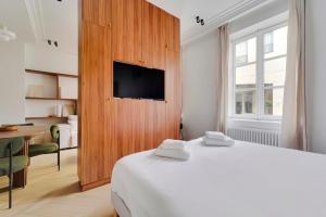 um quarto com uma cama, uma televisão e uma mesa em Musée Picasso em Paris