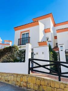 Uma casa branca com uma cerca preta à frente. em Jolie maison à Cabopino Marbella em Marbella