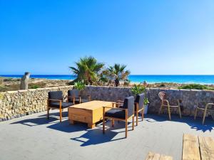 een patio met een tafel en stoelen en het strand bij La Casa de Piedra a orillas del mar in Vejer de la Frontera