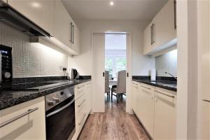 een keuken met witte kasten en zwarte aanrechtbladen bij Period Character with Modern Comforts In Monkstown in Blackrock