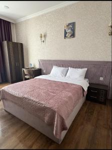 ein Schlafzimmer mit einem großen Bett mit einer lila Decke in der Unterkunft Buta Hotel Berde 