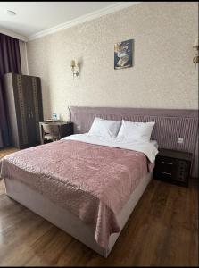 a bedroom with a large bed with a purple blanket at Buta Hotel Berde in Bǝrdǝ